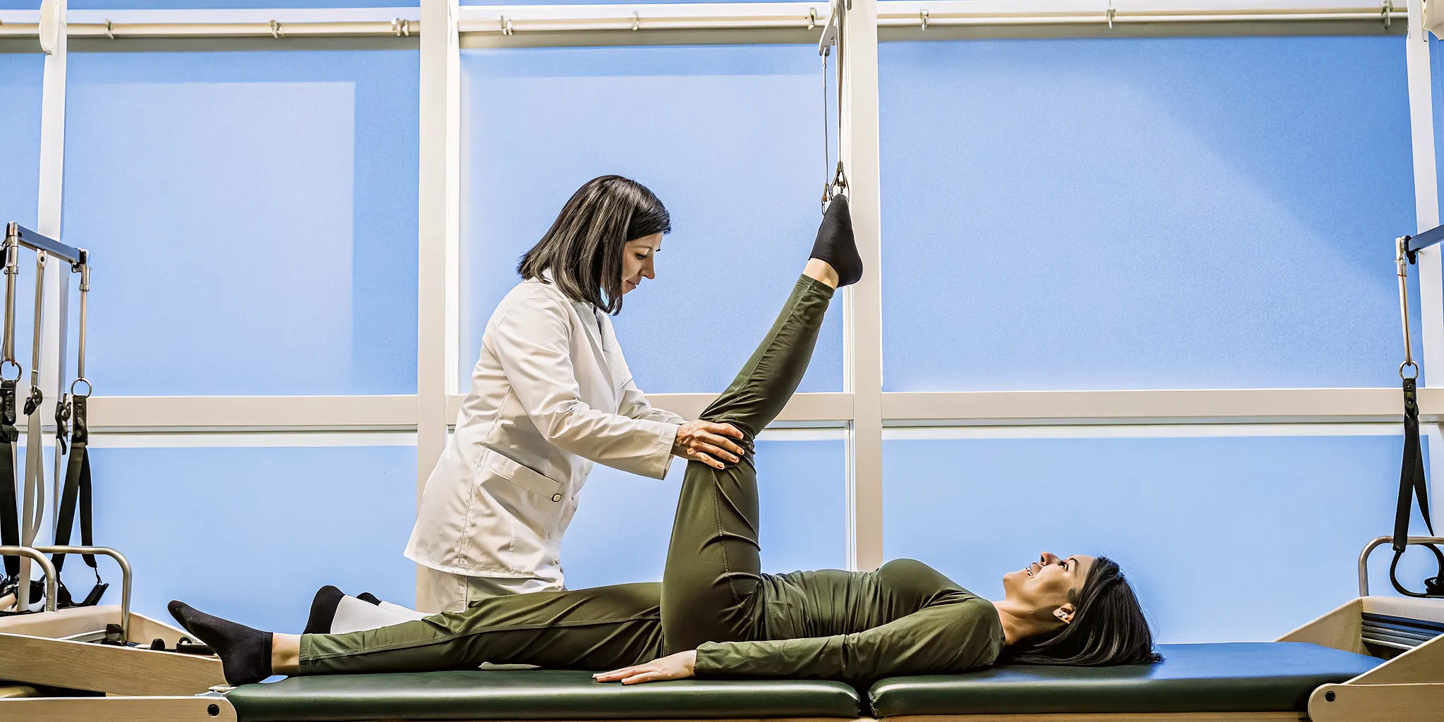 Physical therapist in Brooklyn guiding a patient through core stability exercises on a Pilates reformer for back pain recovery