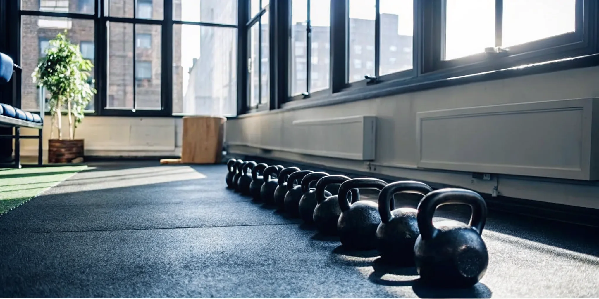 Functional fitness equipment and kettlebells neatly arranged on dark turf inside a premium Manhattan gym
