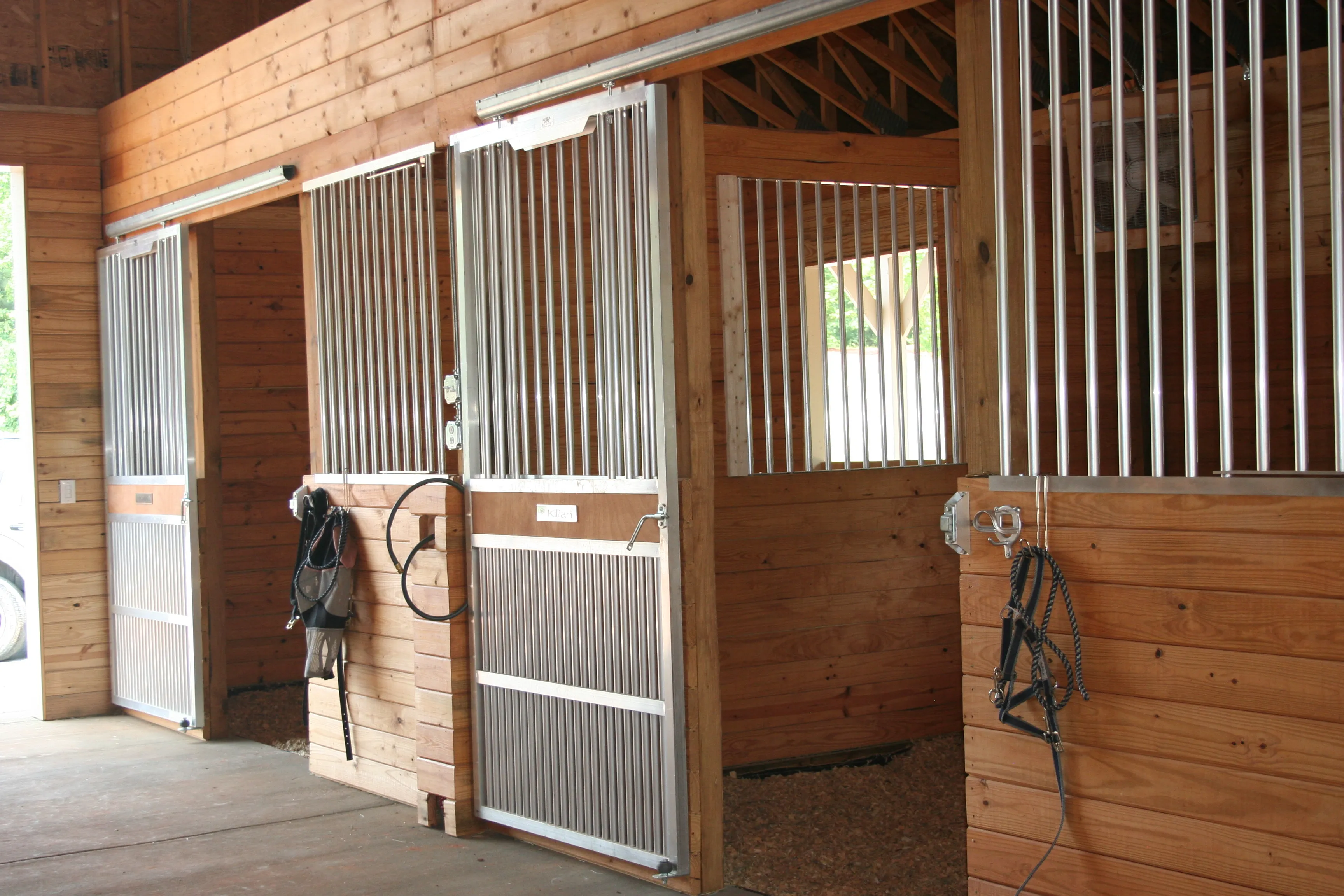 Installed silver aluminum-framed sliding door in a horse barn interior