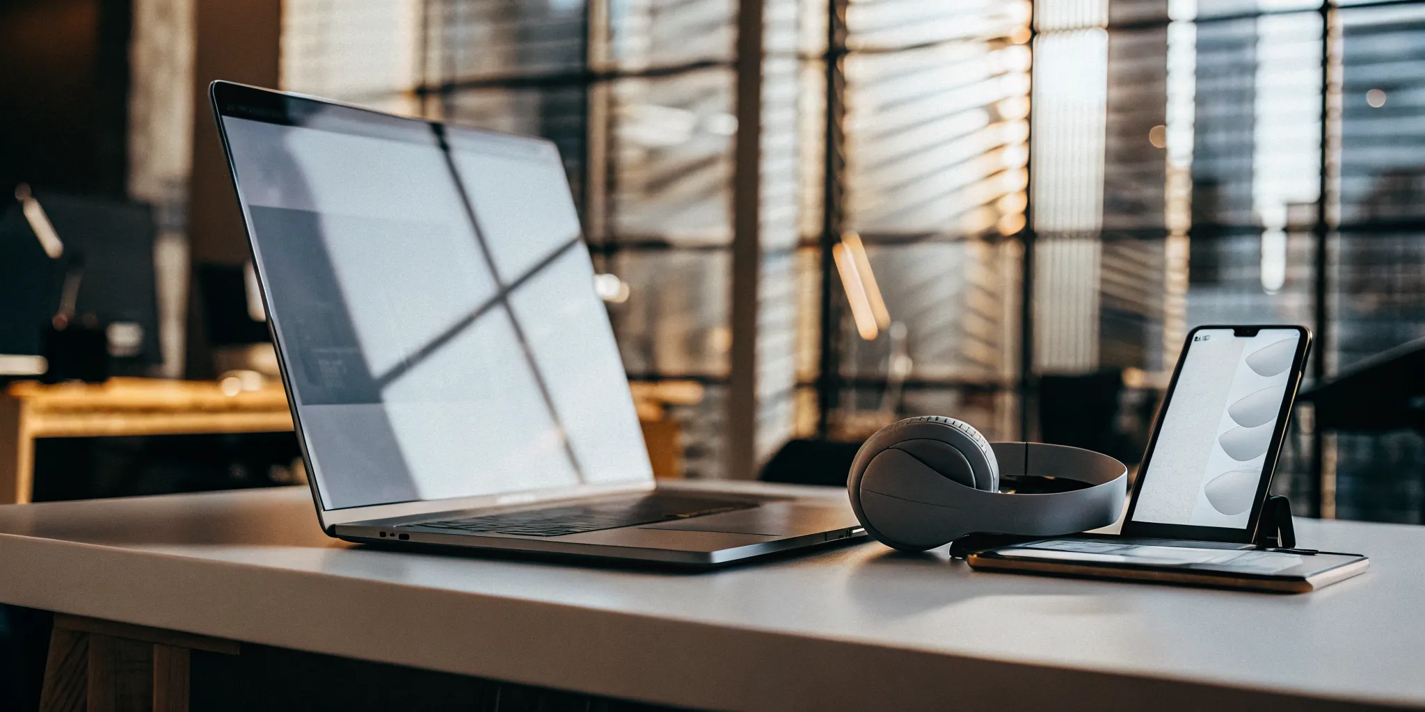 Laptop and headphones on a desk for a customer service agent reviewing a call script.