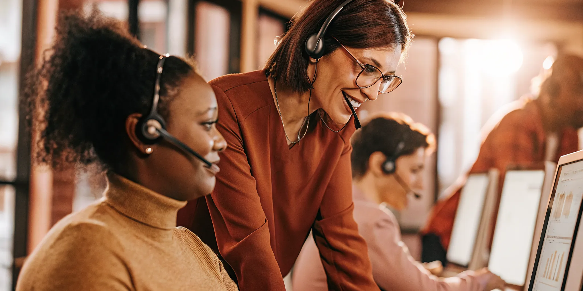 New contact center agent being guided through training by an experienced mentor in a modern contact center environment