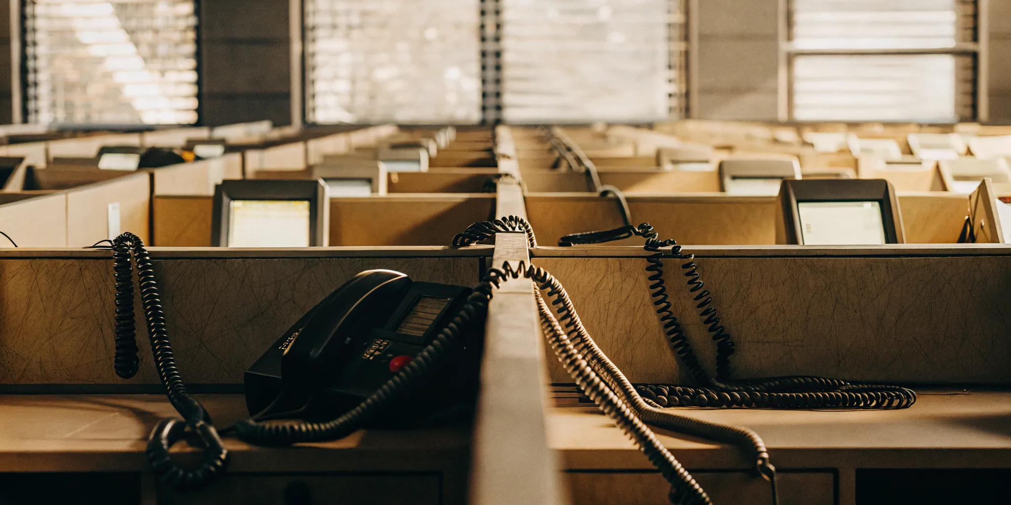 Outdated technology like old phones and monitors in an empty legacy contact center.