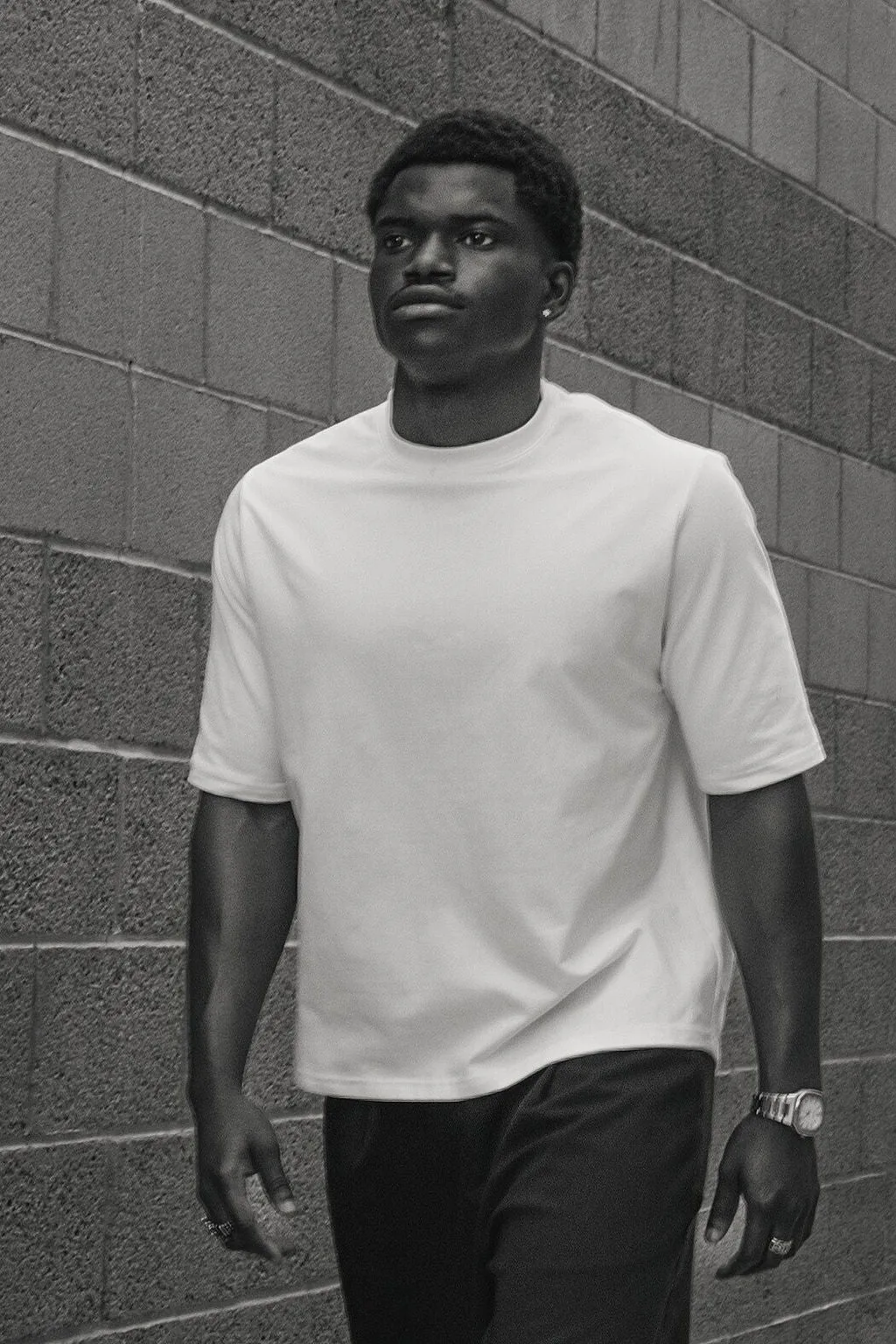 Male model wearing a white SPHILISTINE T-shirt in an urban setting