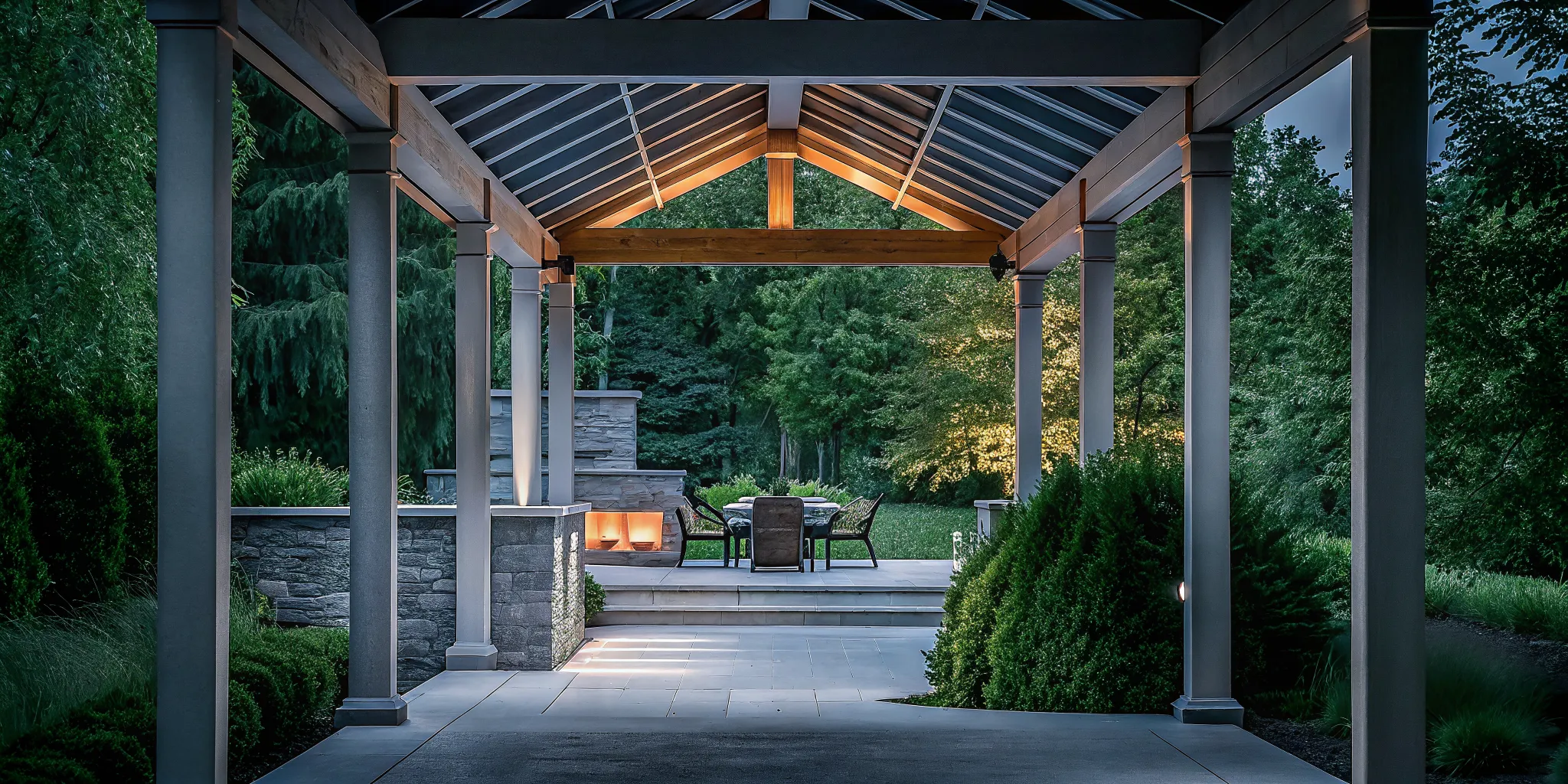 Luxury timber-frame backyard pavilion with exposed wood beams and stone columns in an evening landscape setting