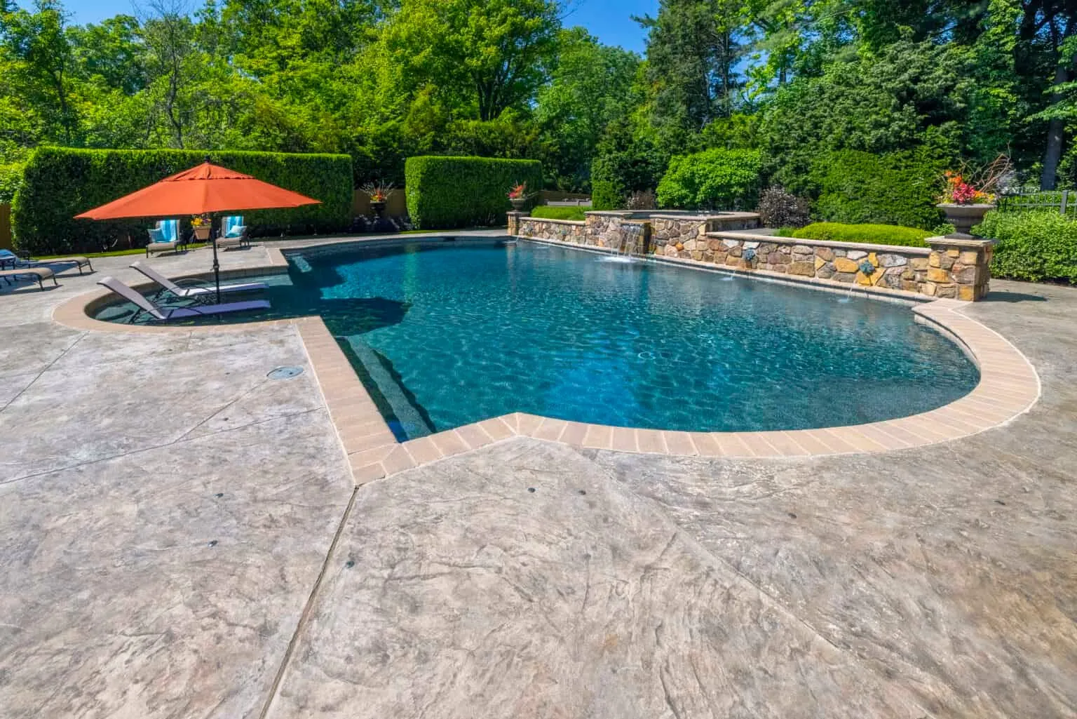 Luxury outdoor living space with pool, stone patio, and professional landscaping by DiSabatino Inc.