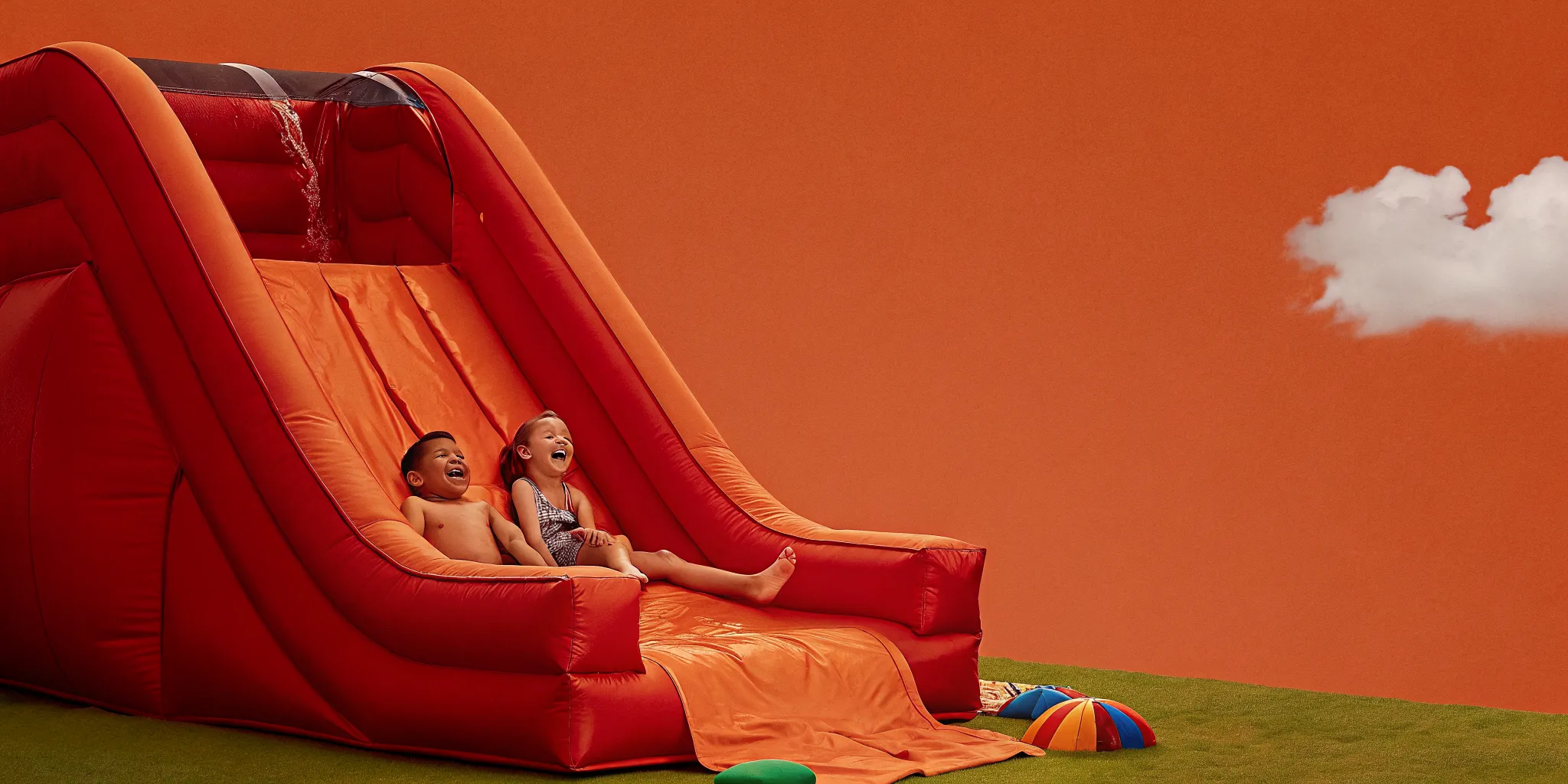 Backyard party with a large inflatable water slide set up on a grassy lawn on a sunny summer day