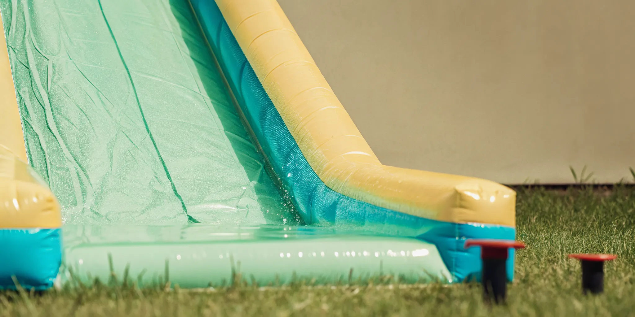 Bright inflatable water slide in a backyard with blue slide lanes and water flowing down the vinyl surface