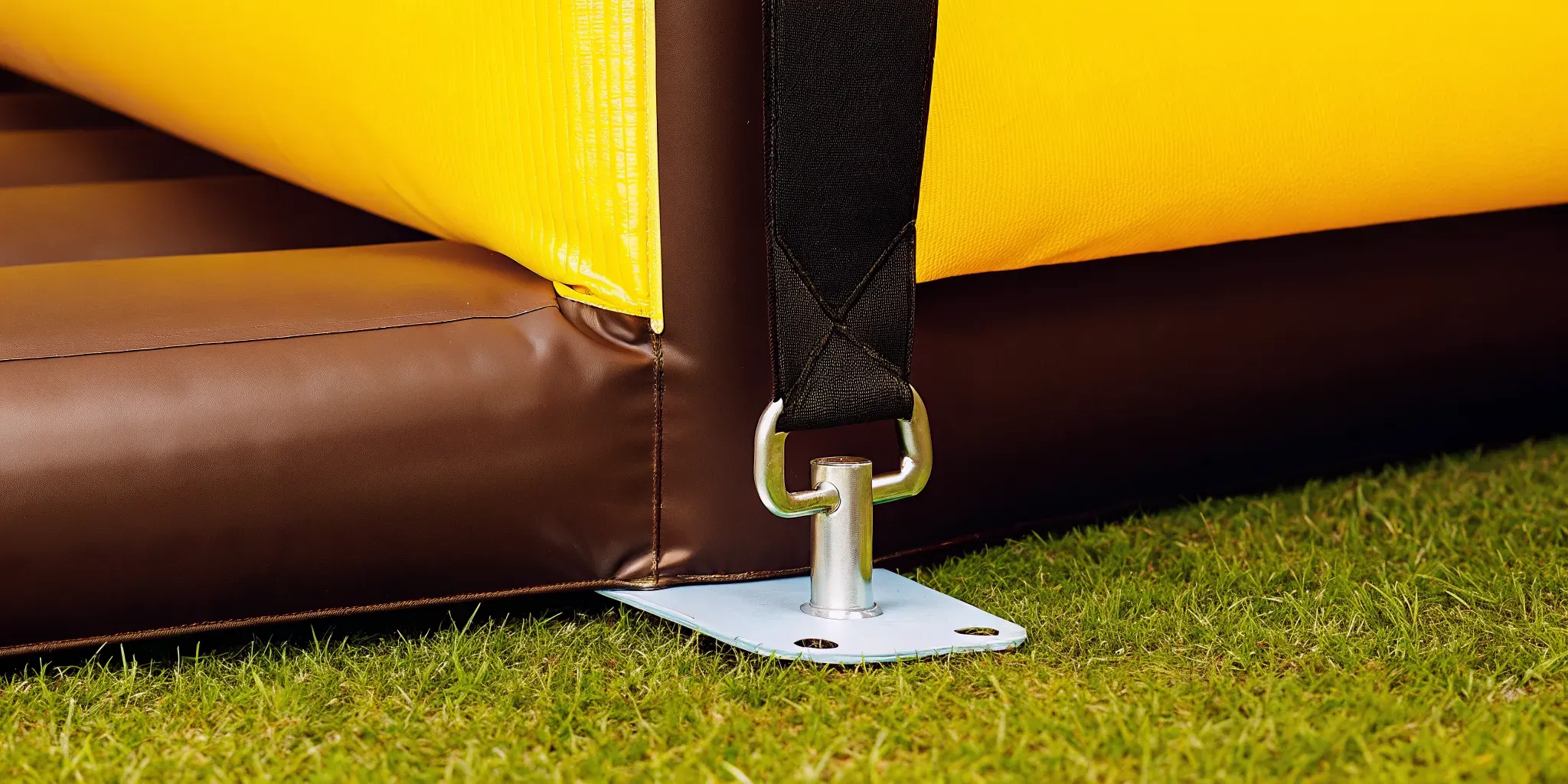 Safety anchor stake securing a bounce house to the grass at a backyard party setup by AJT Bounce in Massachusetts