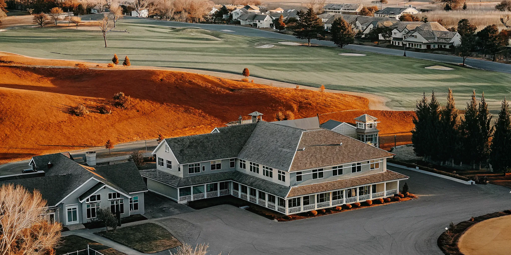 Aerial perspective of a championship golf course with a historic clubhouse surrounded by luxury homes