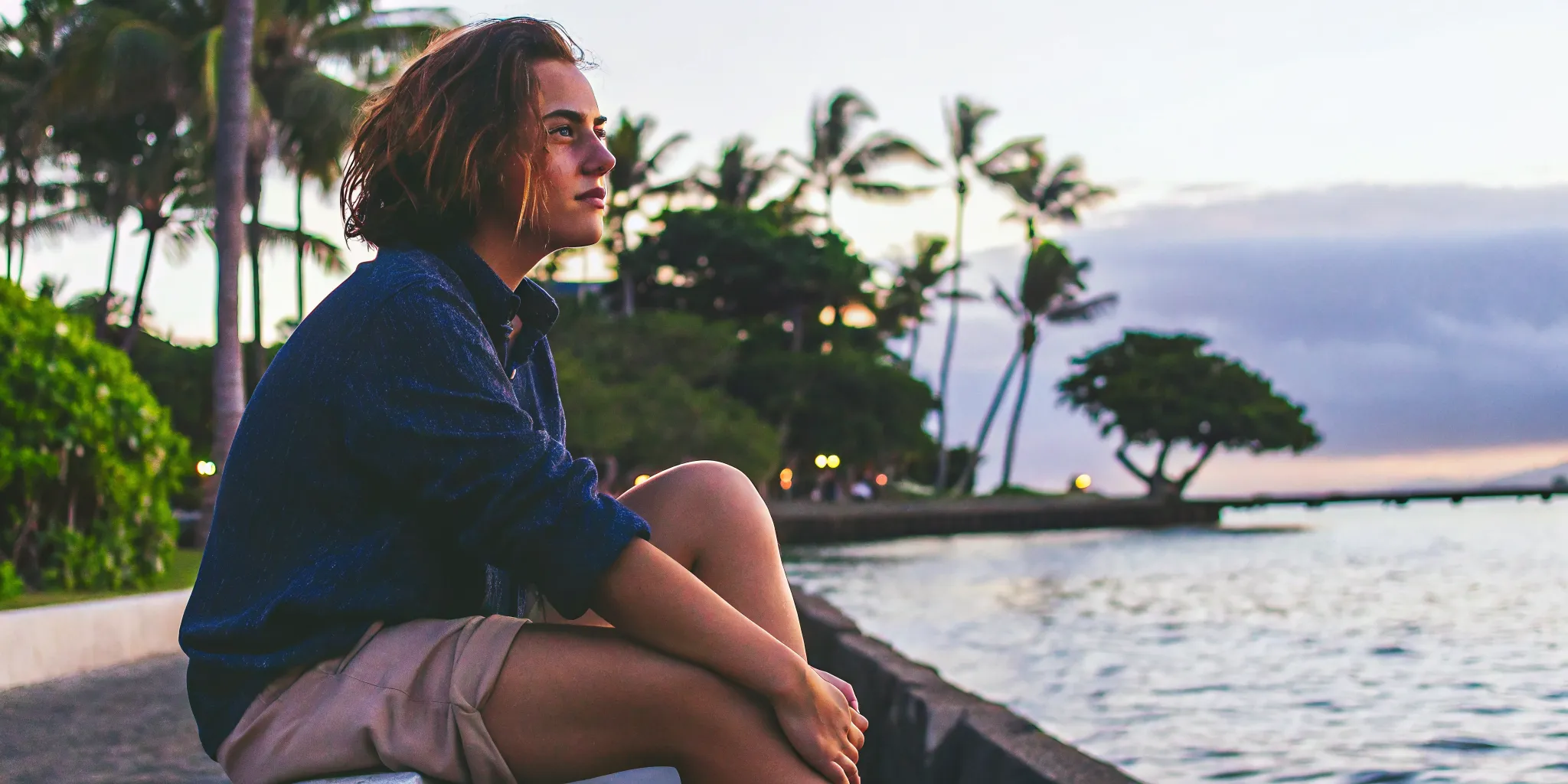 A person sitting by the Hawaii shoreline, peaceful and reflective at sunset