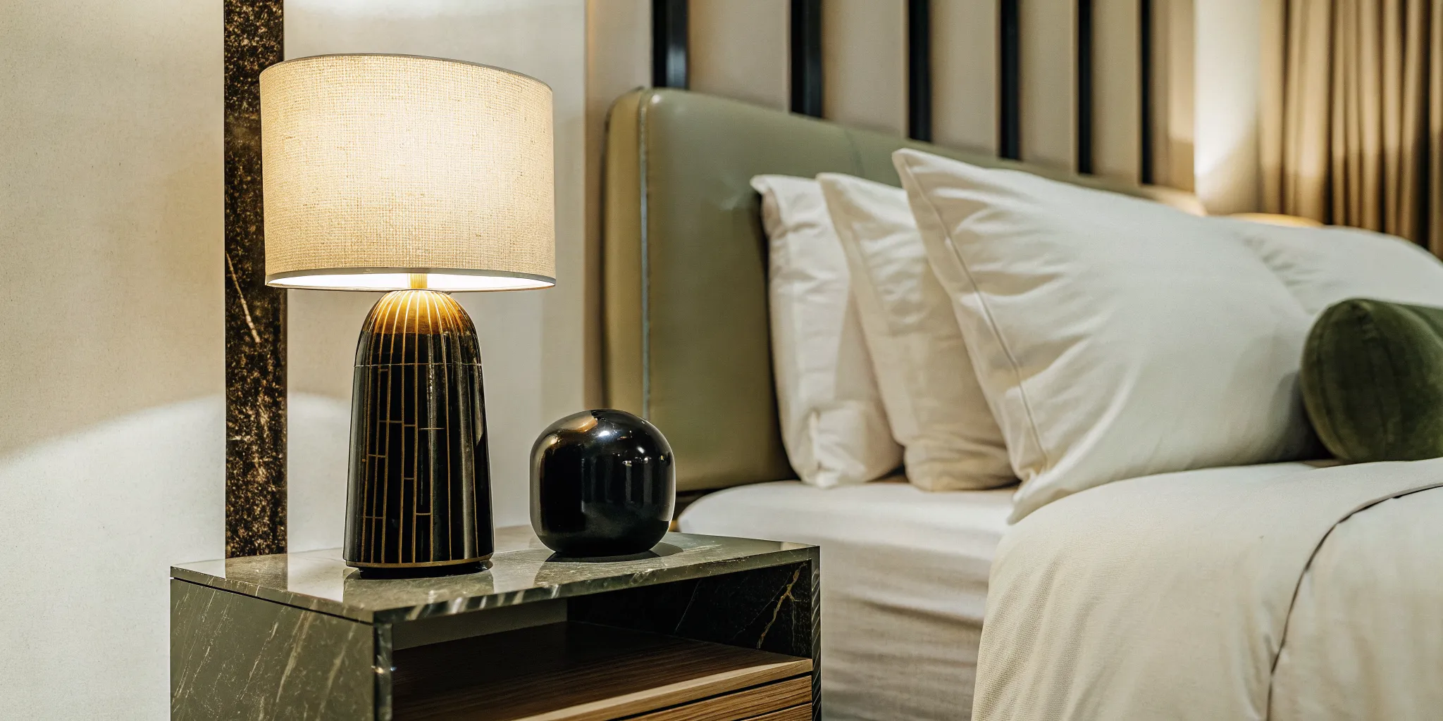 A modern bedside setup with a handcrafted sculptural ceramic bedside table lamp in warm light, minimalist decor