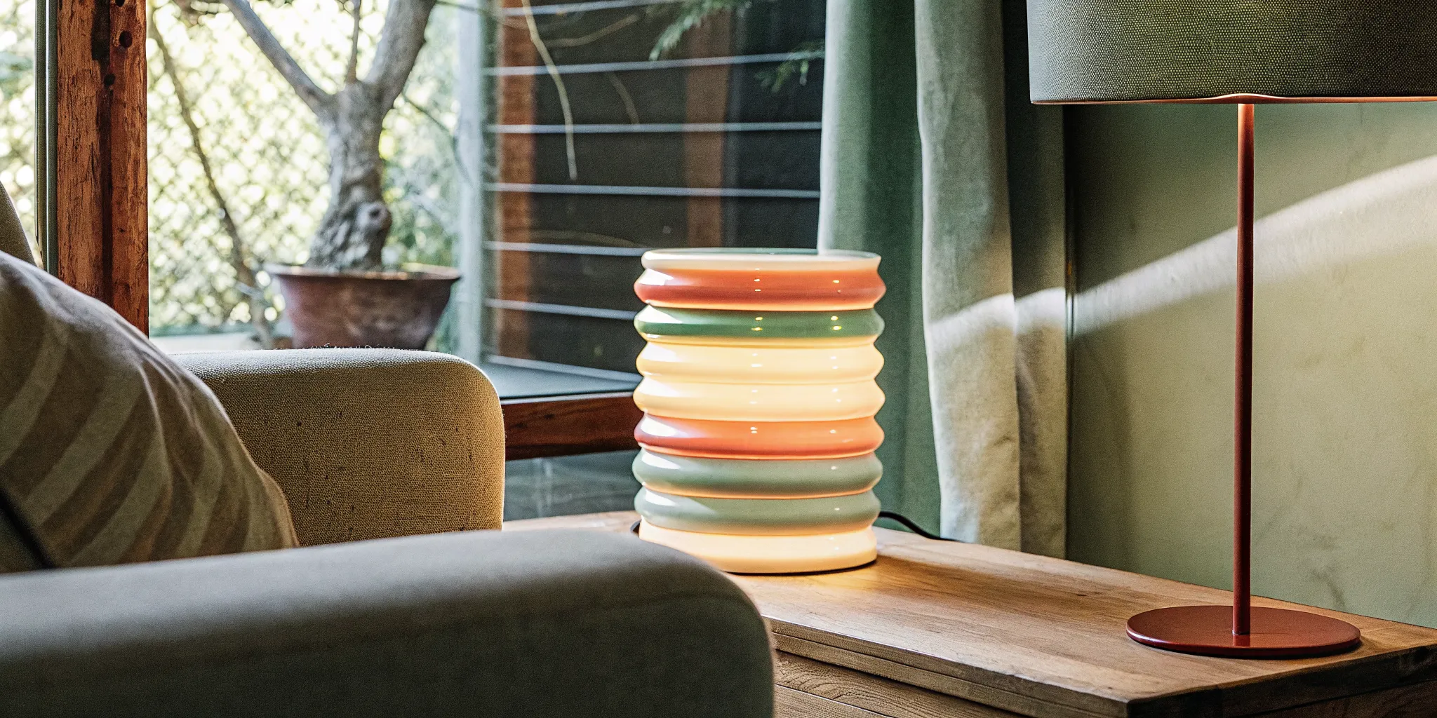 Sculptural table lamp casting warm light on a neutral armchair in a cozy living room corner