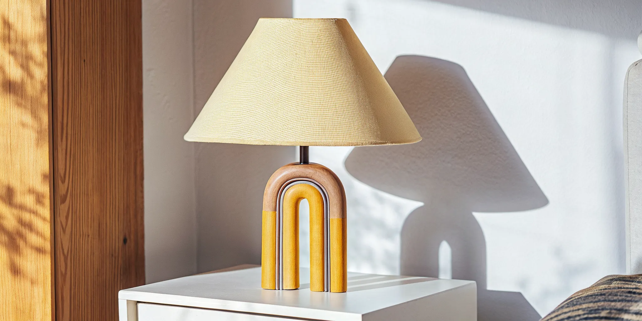 A bold color-blocked ceramic and steel statement table lamp on a white side table