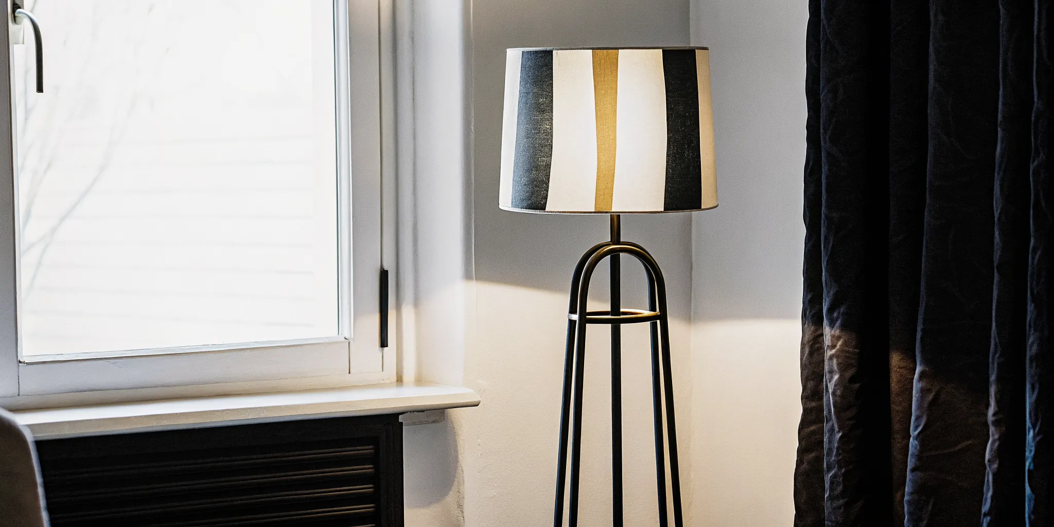 A sculptural steel and ceramic floor lamp casting warm light in a minimalist living room corner