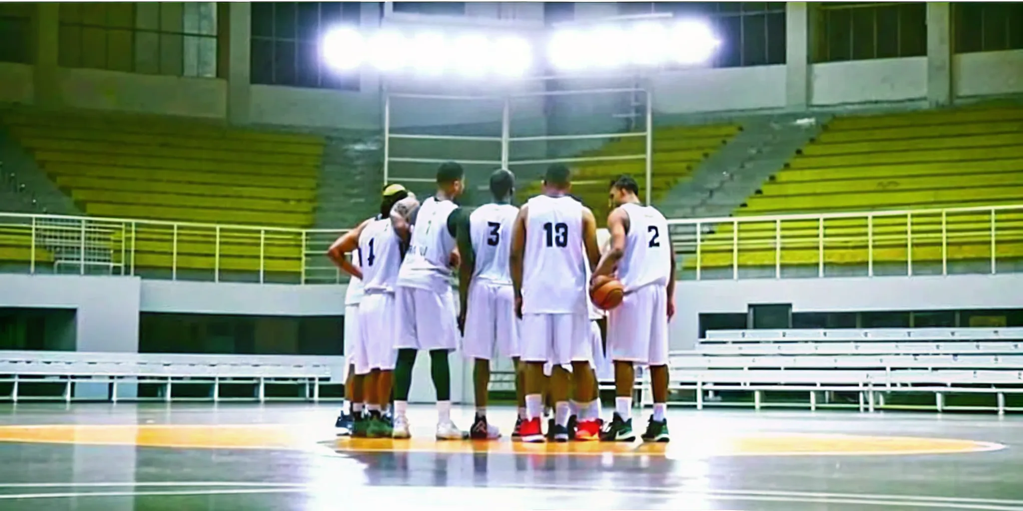 Basketball players wearing numbered jerseys on an indoor court