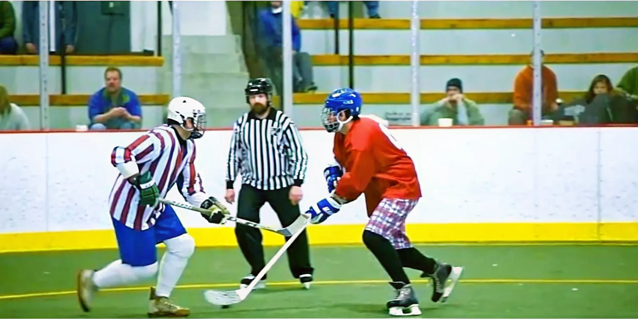 Box lacrosse players competing in an indoor arena while wearing colorful jerseys