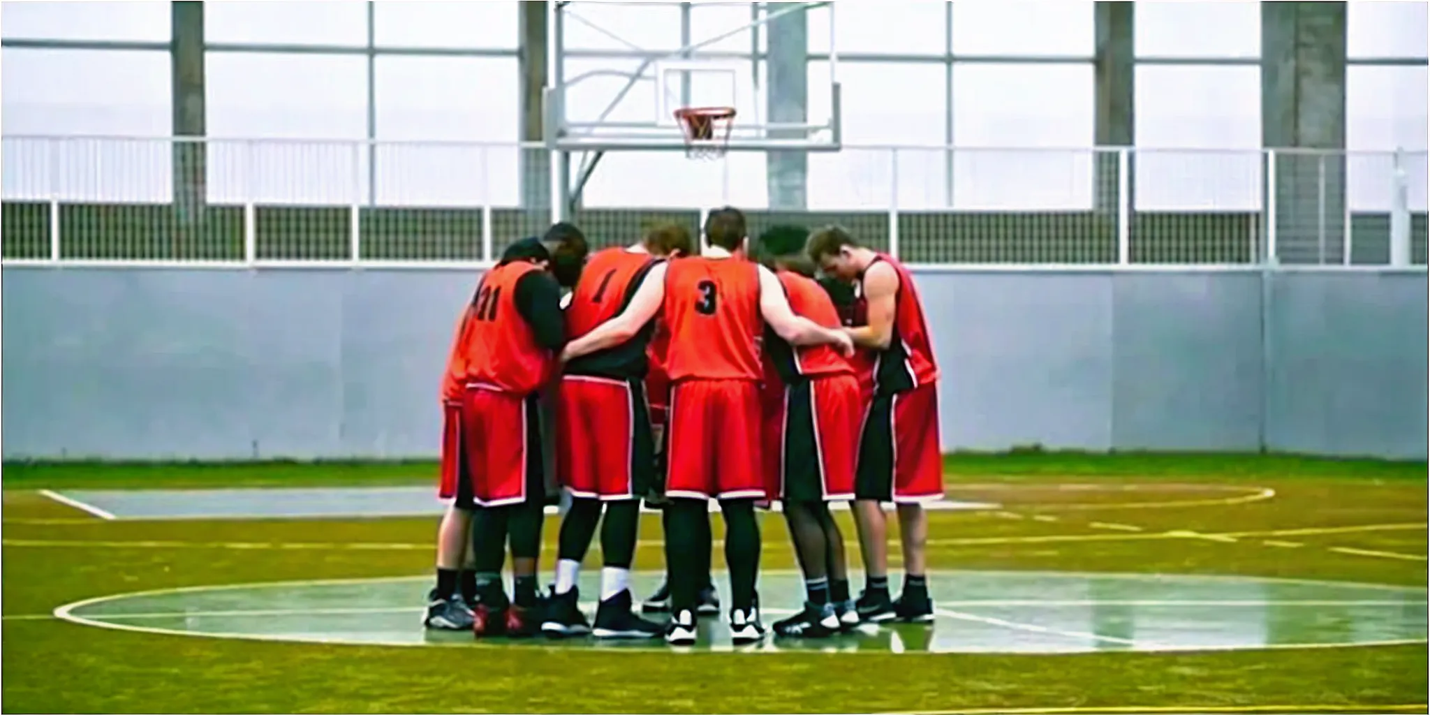 Basketball team huddling in coordinated custom uniforms on an indoor court