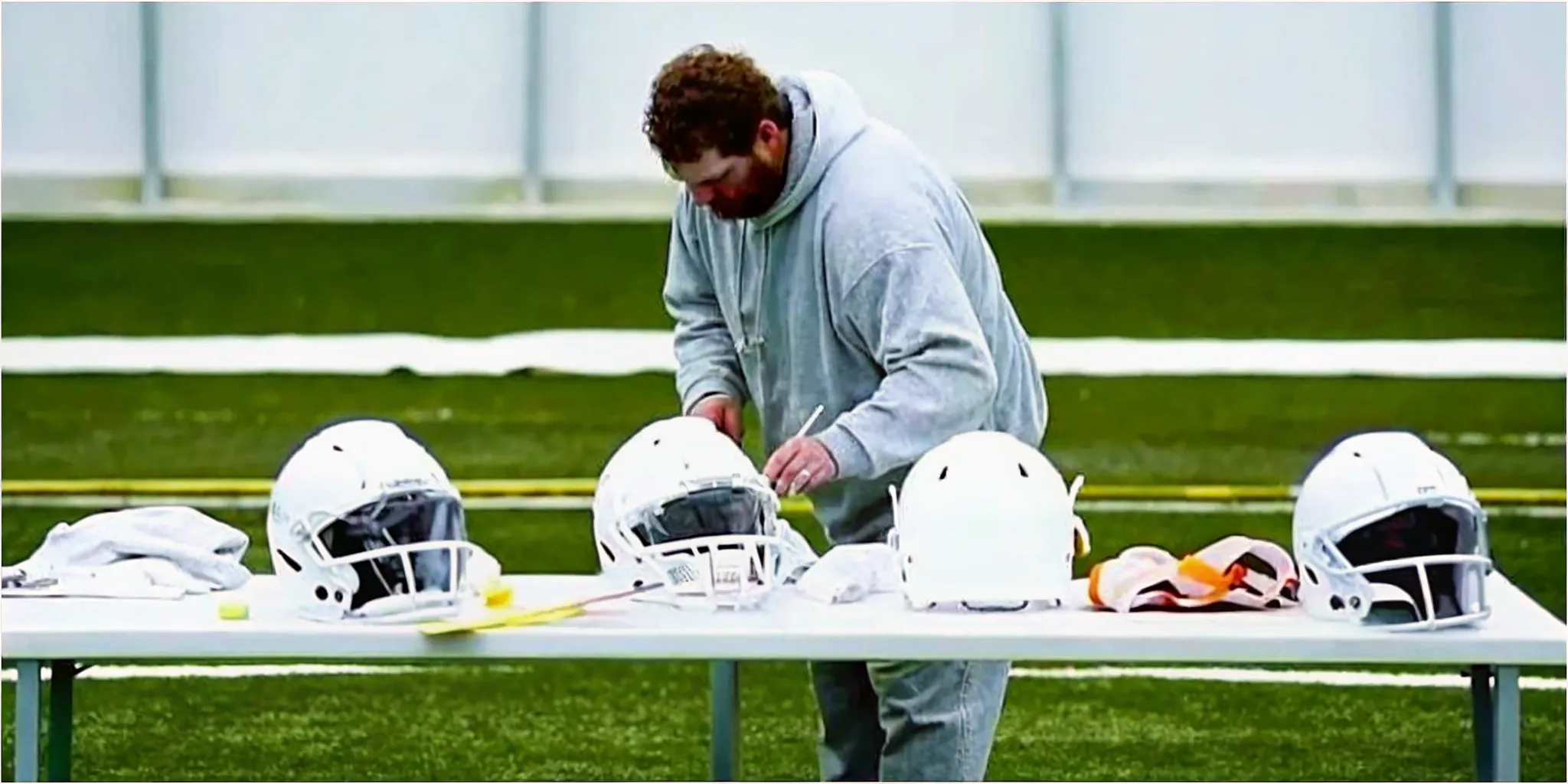 Equipment manager installing a decal on a box lacrosse helmet