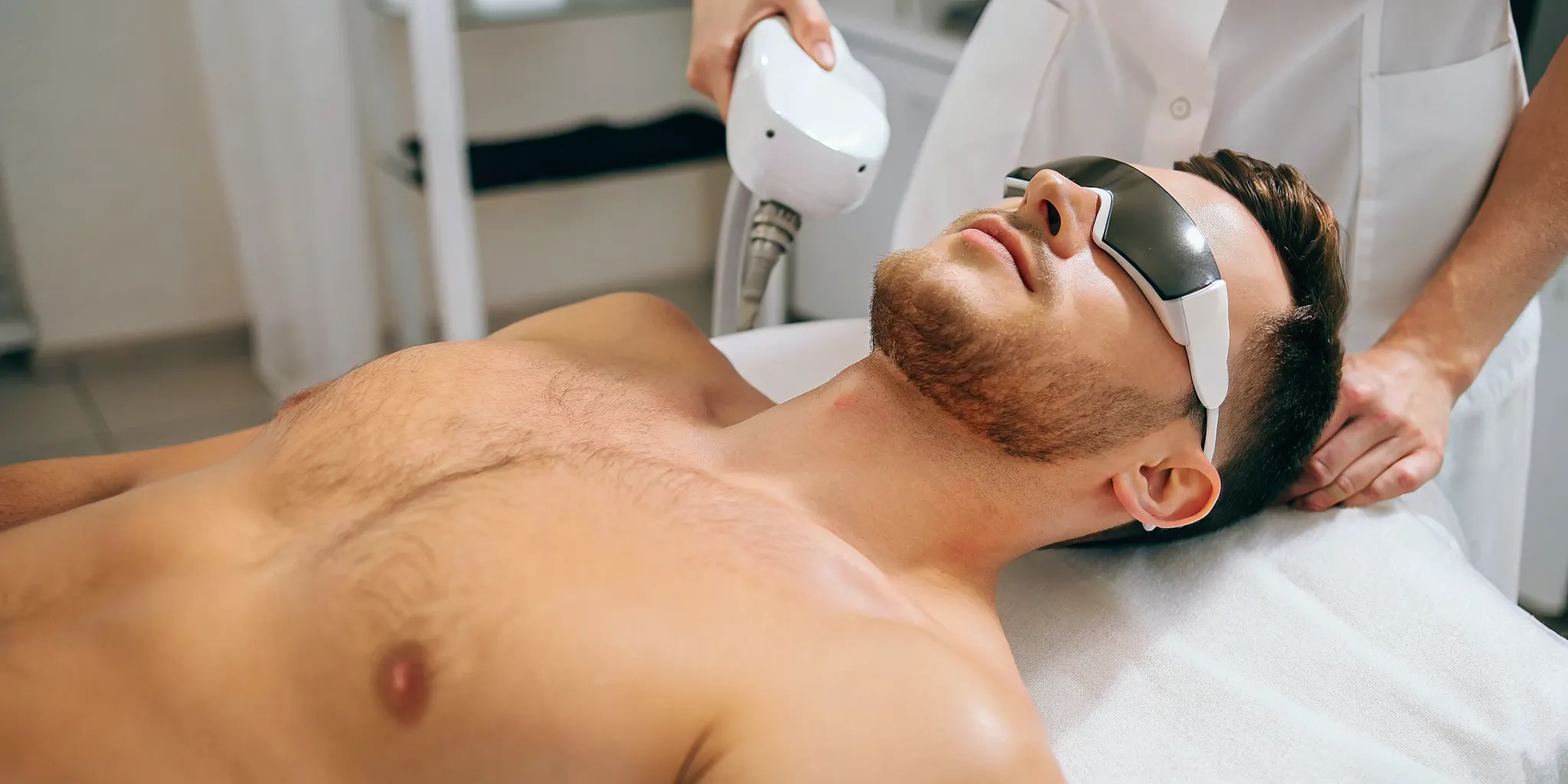 Male client in a medical spa treatment room speaking with a professional aesthetician before a laser session