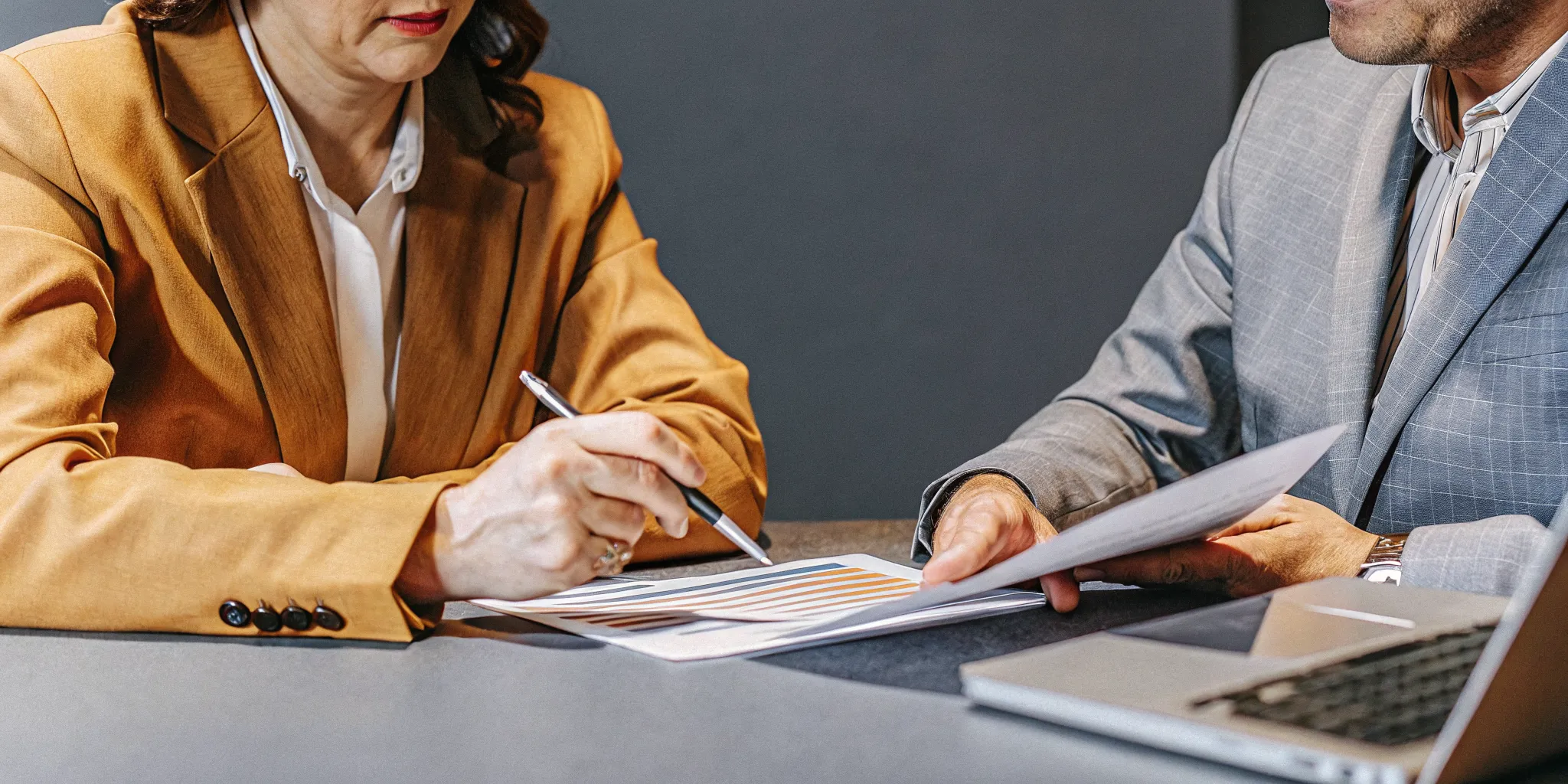 CEO and health insurance advisor reviewing financial charts and benefits cost analysis documents on a desk