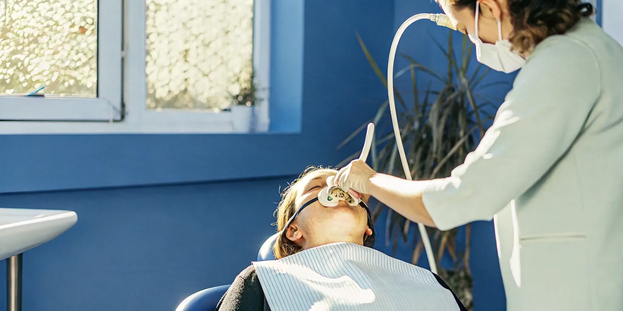 Patient reclining comfortably with a nasal mask for nitrous oxide in a modern dental chair