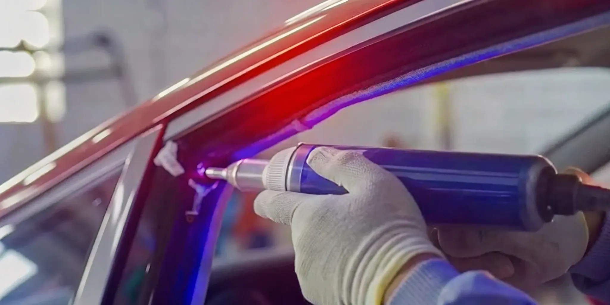 A professional auto glass technician carefully applying high-strength urethane adhesive to the edge of a new windshield, illustrating the precision and quality materials required