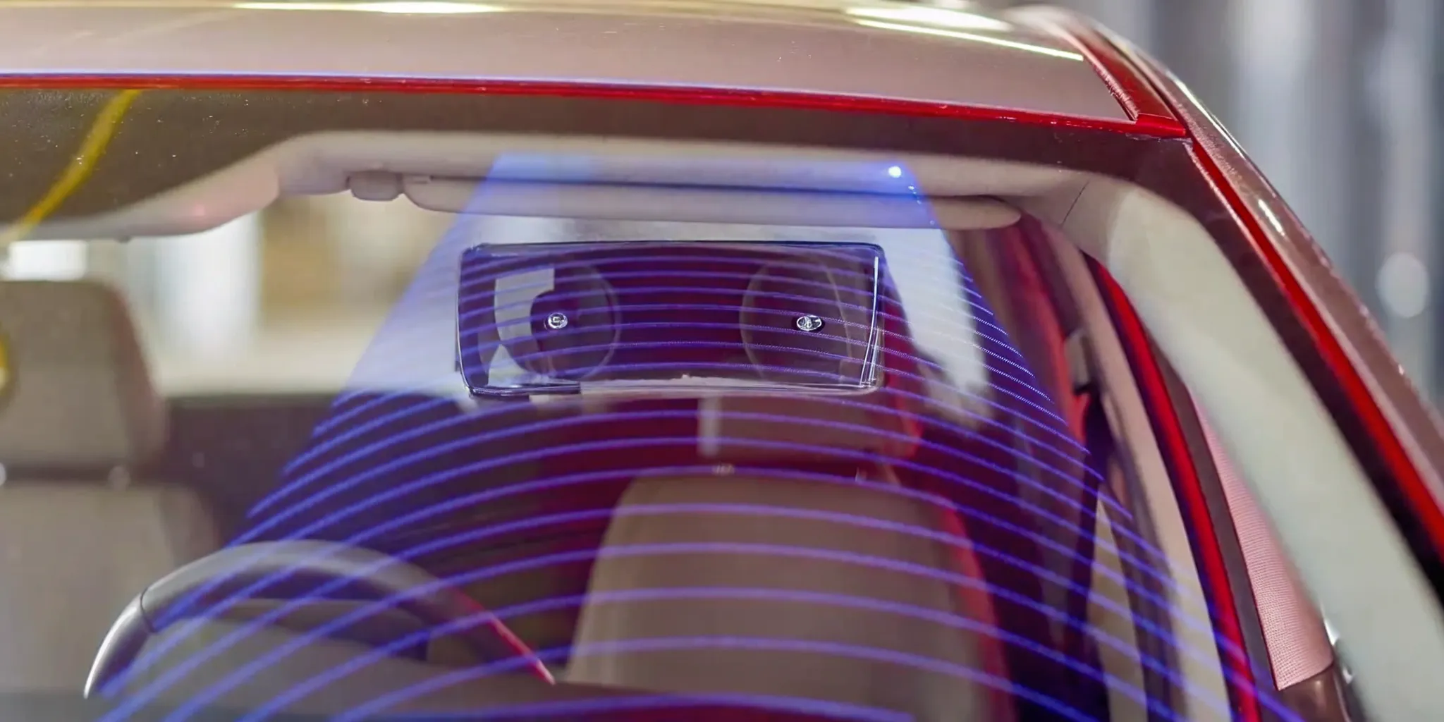 Close-up of ADAS camera module mounted behind a vehicle windshield showing the sensor housing