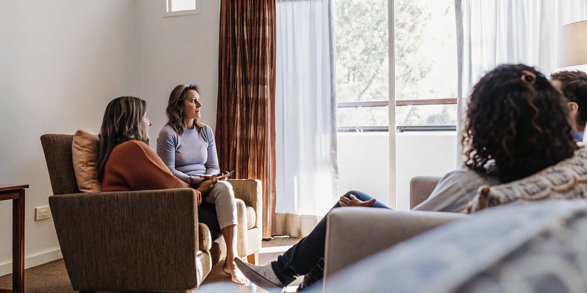 Small group therapy session with a therapist and eight adults in a warm, sunlit room at a Sarasota counseling center