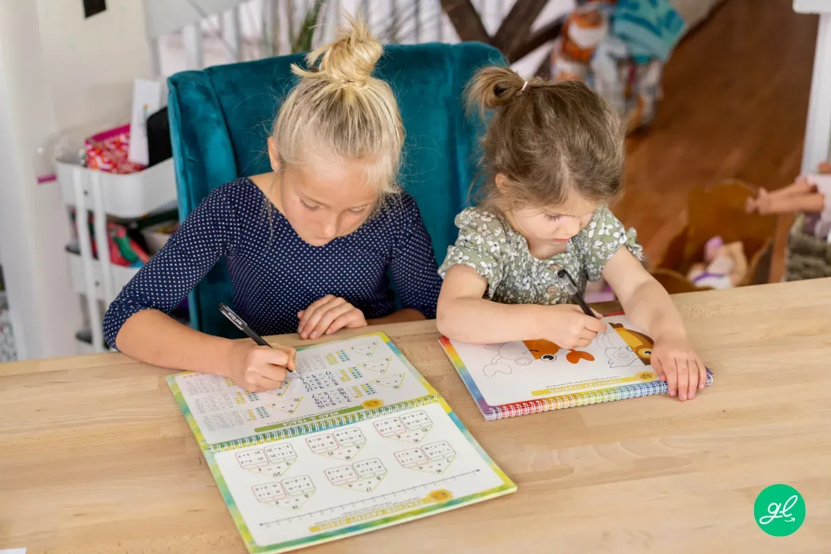 Child sitting at a table practicing handwriting in a reusable grooved workbook