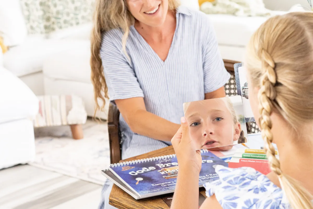 Child tracing cursive letter forms in a grooved handwriting workbook