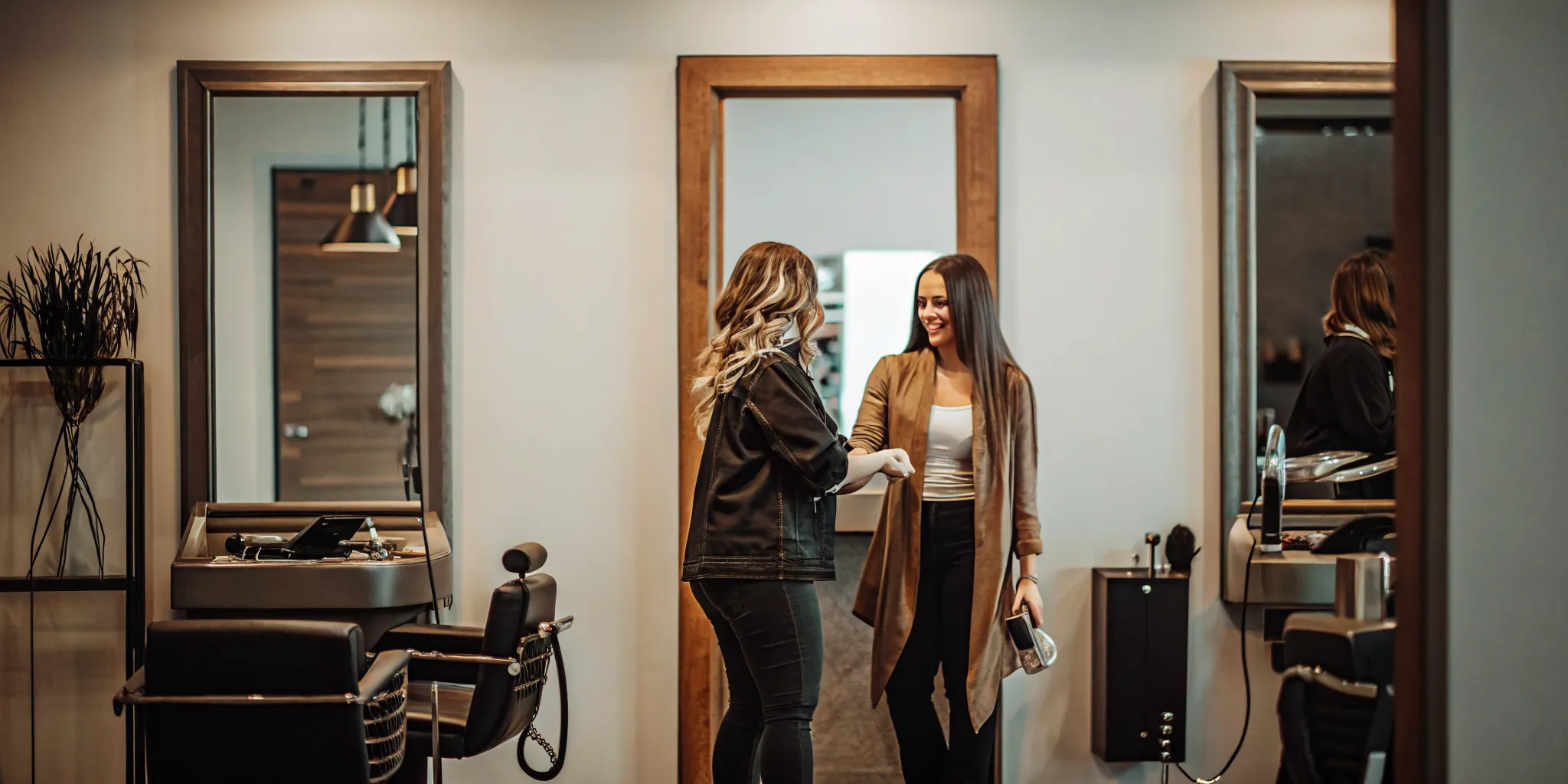 Independent beauty professional welcoming a client into a polished private salon suite