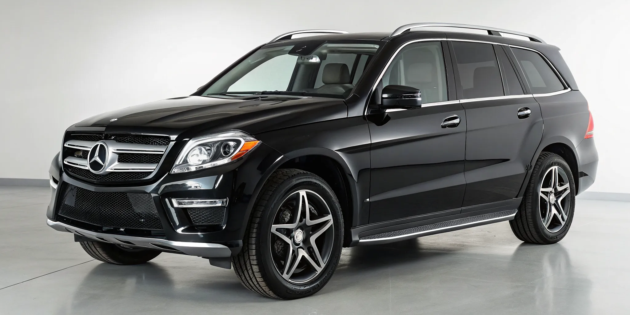 A black pre-owned Mercedes SUV on display inside a dealership showroom.