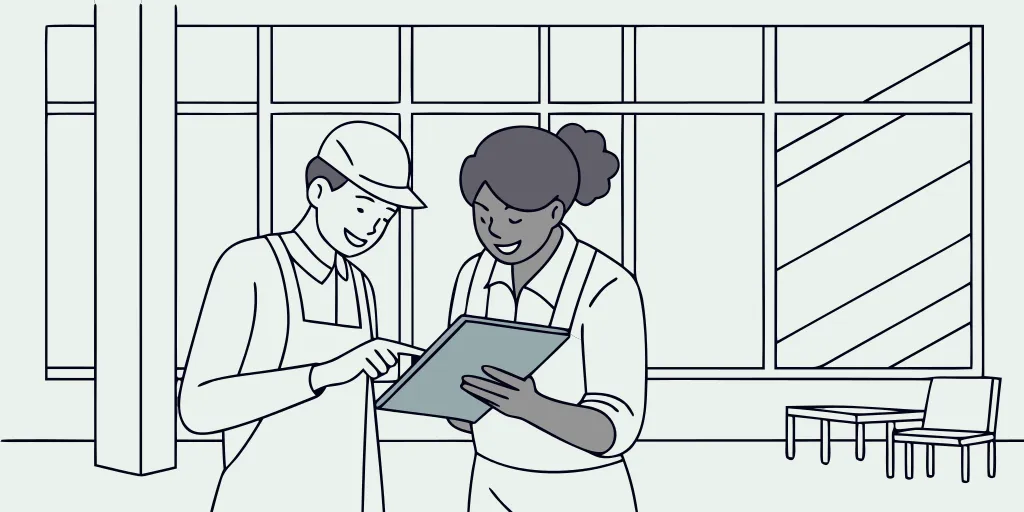 Two restoration business owners reviewing growth metrics on a tablet in a bright modern office
