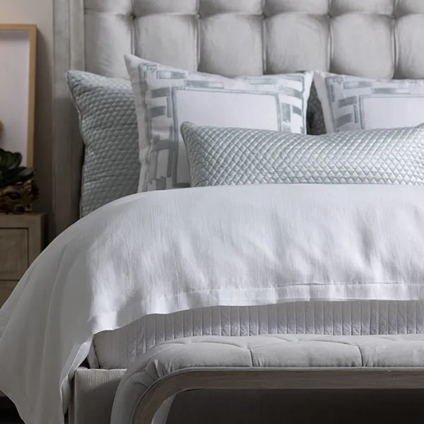 Aquamarine bedding layers and decorative pillows styled for a luxury upholstered bed
