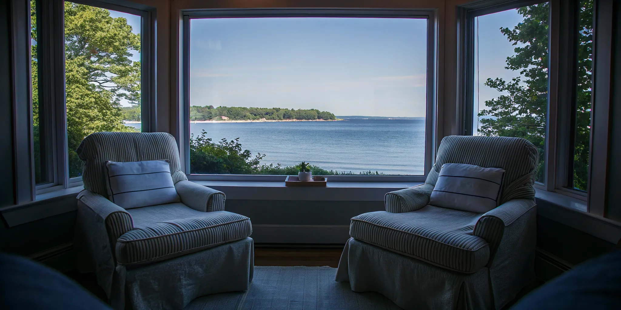 A peaceful coastal therapy room with large windows overlooking a Massachusetts shoreline in a luxury rehab setting