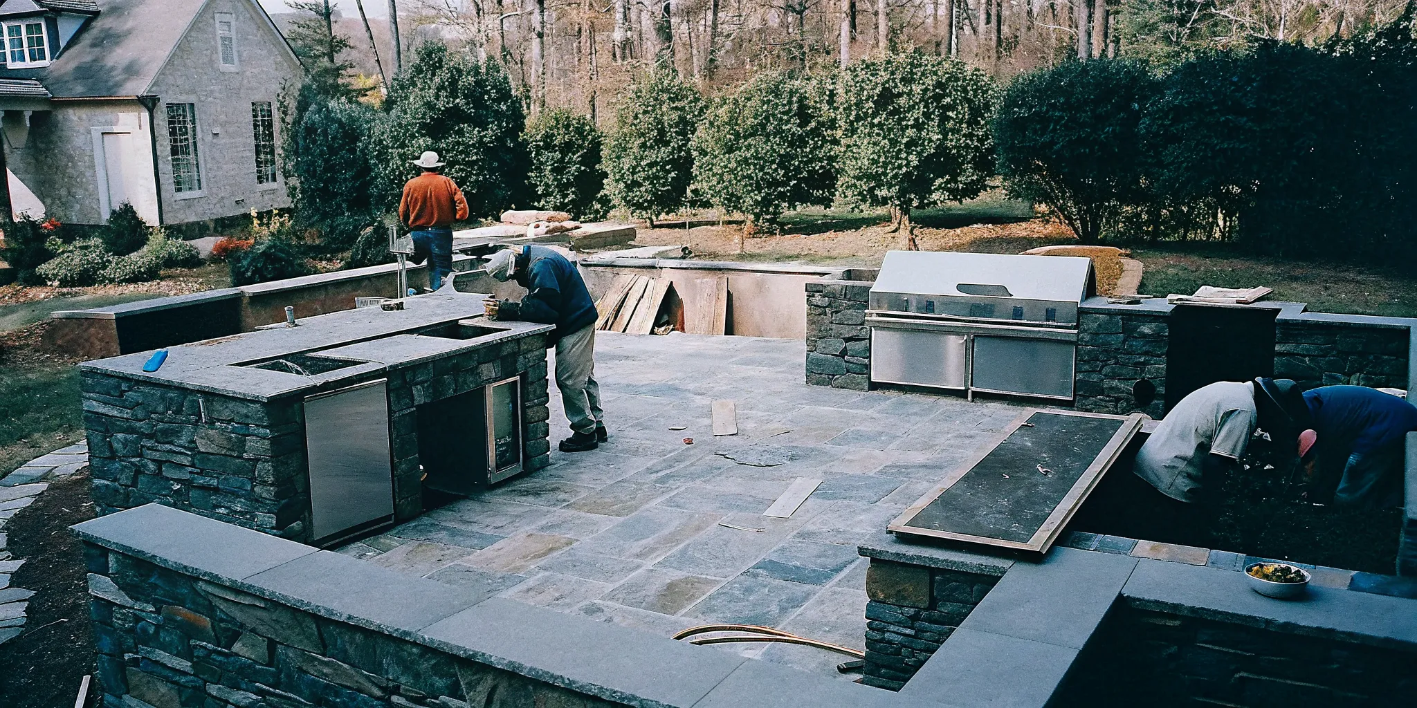 Custom outdoor kitchen under construction with stone veneer in a North Carolina backyard