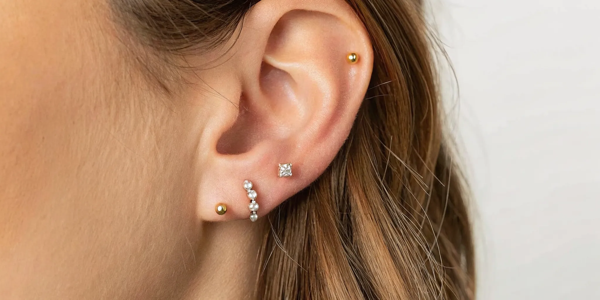 Different ear piercings styled with titanium and gold jewelry
