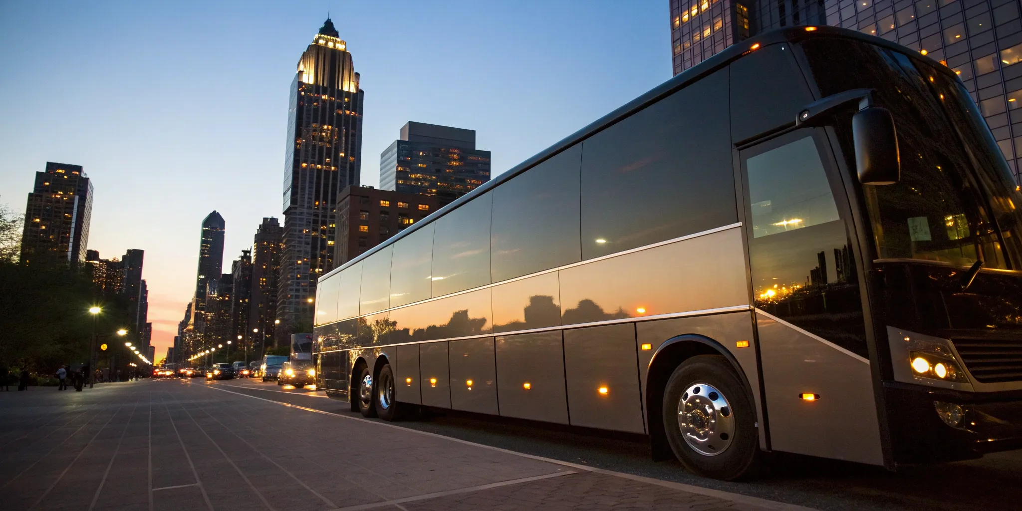 A charter bus rental for group travel parked on a city street at sunset.