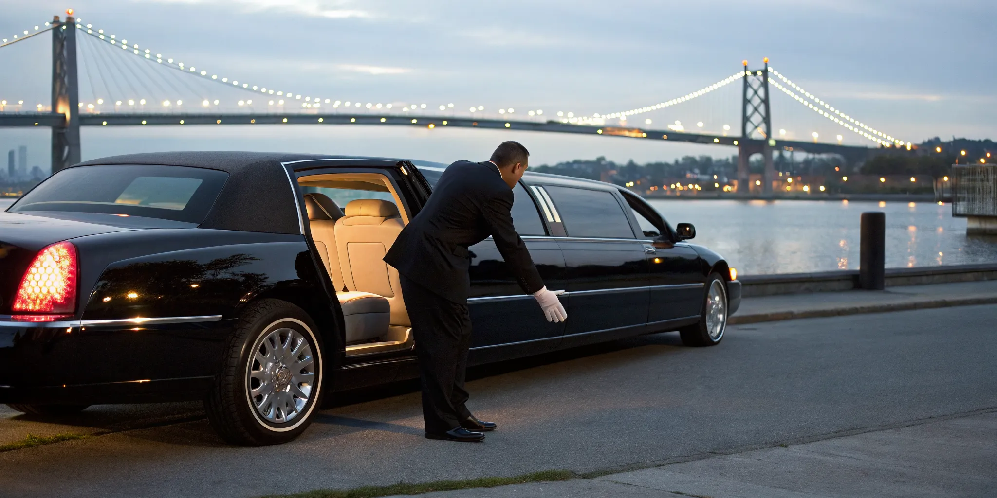 Chauffeur opens a limo door by the bay for a luxury Bayonne event at sunset.