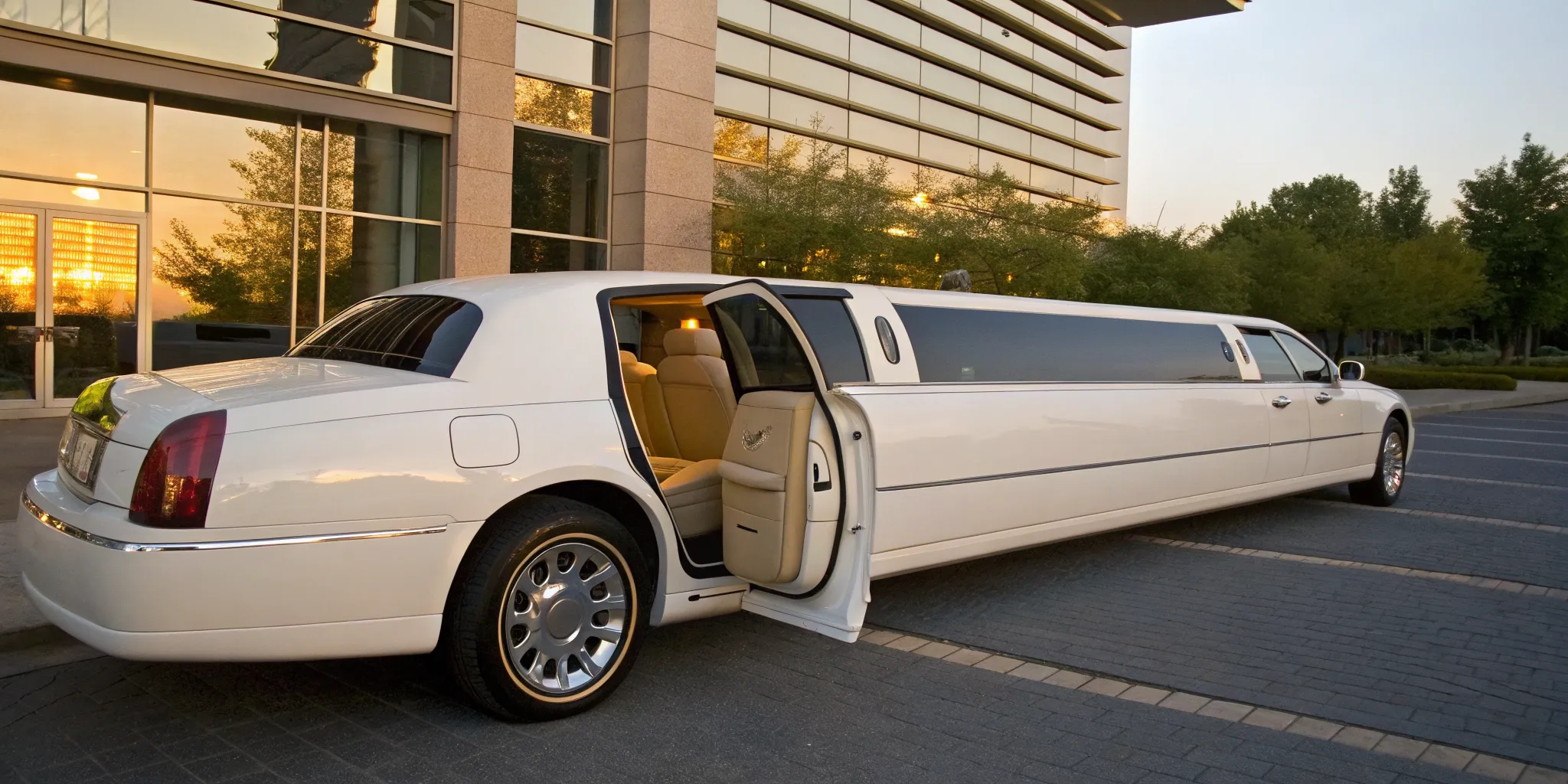 White stretch bridal limo parked in King of Prussia with its door open at sunset.
