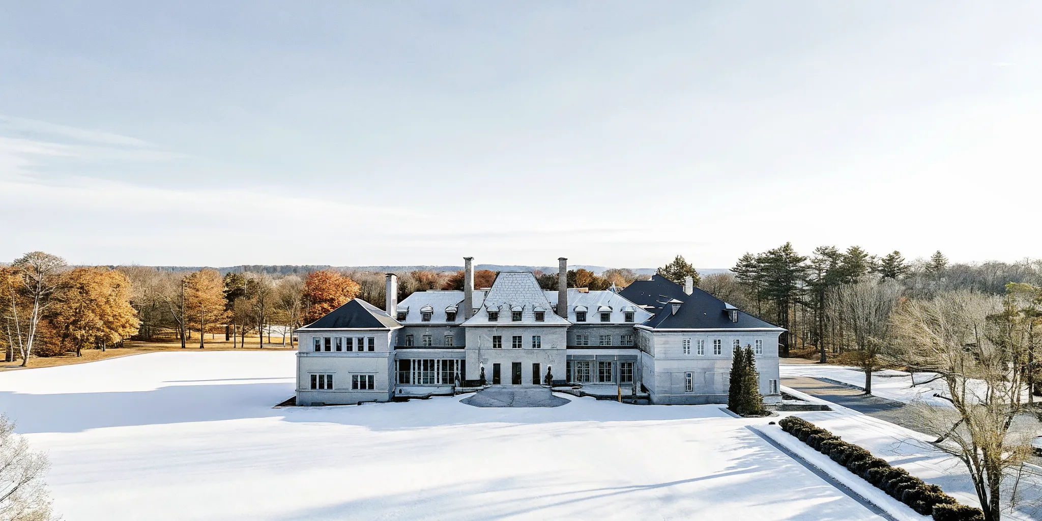 Aerial view of a French Chateau-inspired private estate surrounded by autumn foliage on expansive New England grounds
