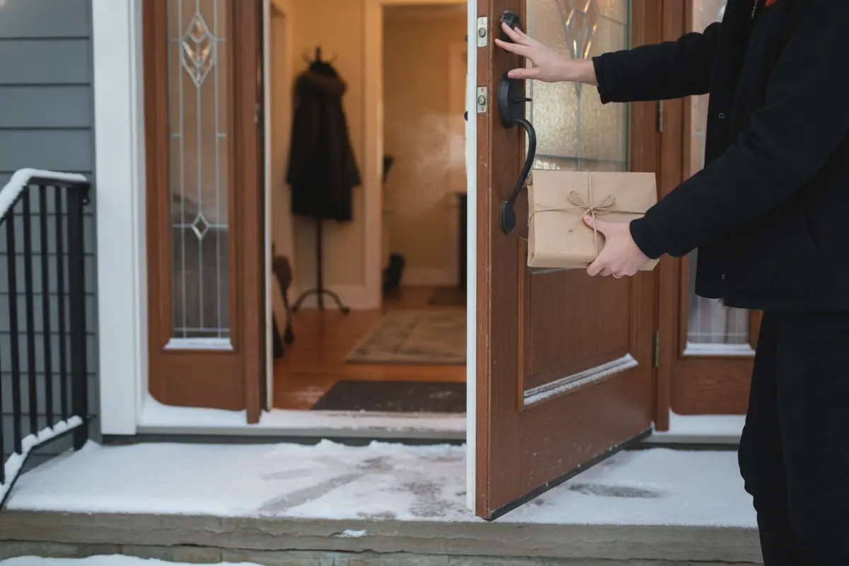 A recipient bringing a delivered candy gift box inside on a winter day