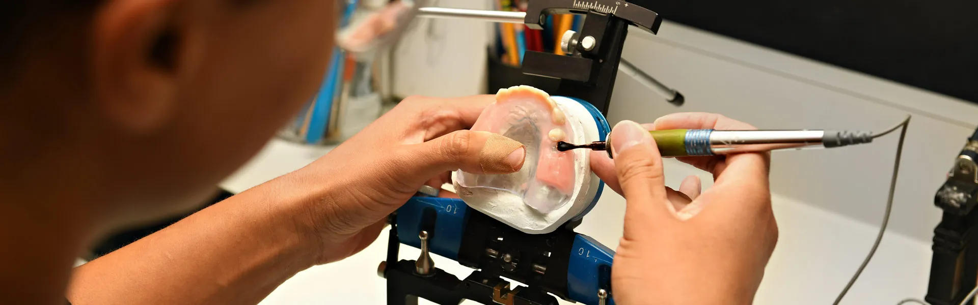 Dental laboratory technician shaping a custom prosthetic restoration