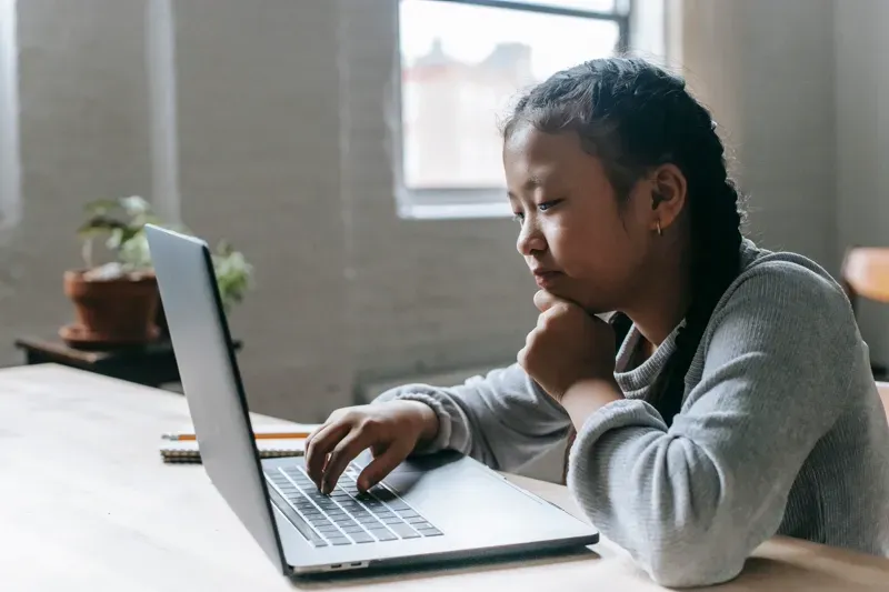 A focused student learning on a laptop during an online class.