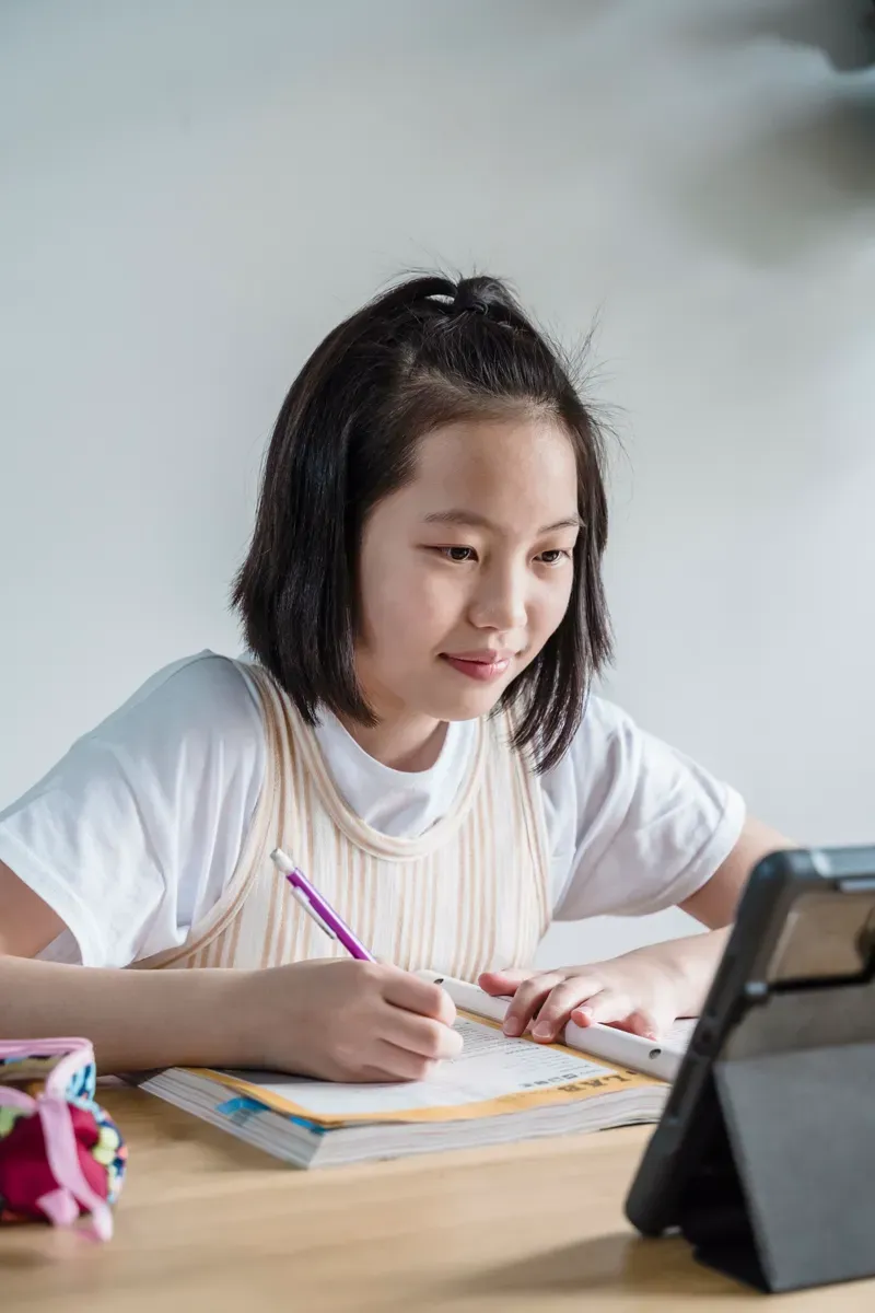 An elementary school student attending live online school from a bright, cozy home workspace.