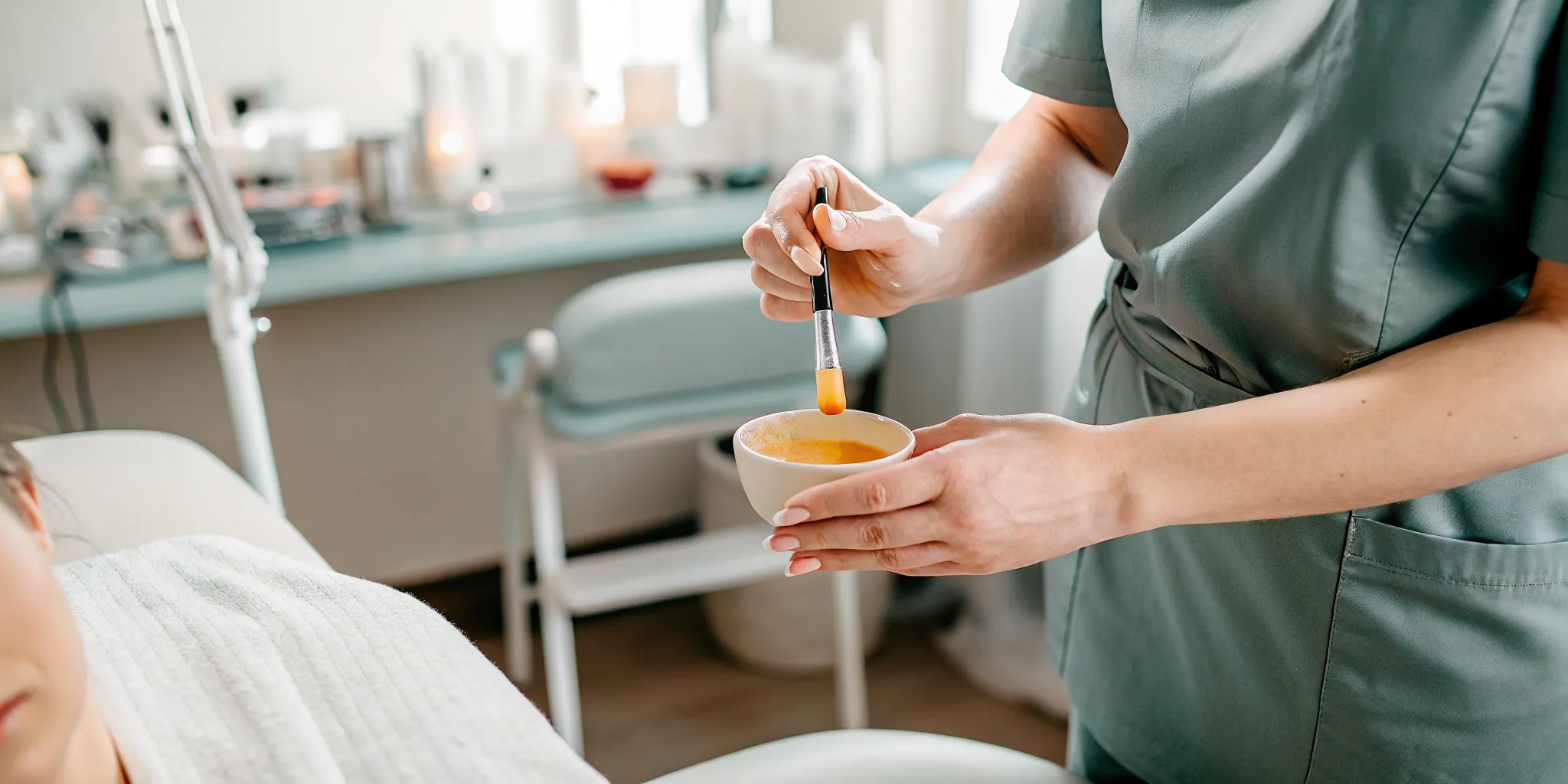 Esthetician applying warm wax in a clean professional treatment room