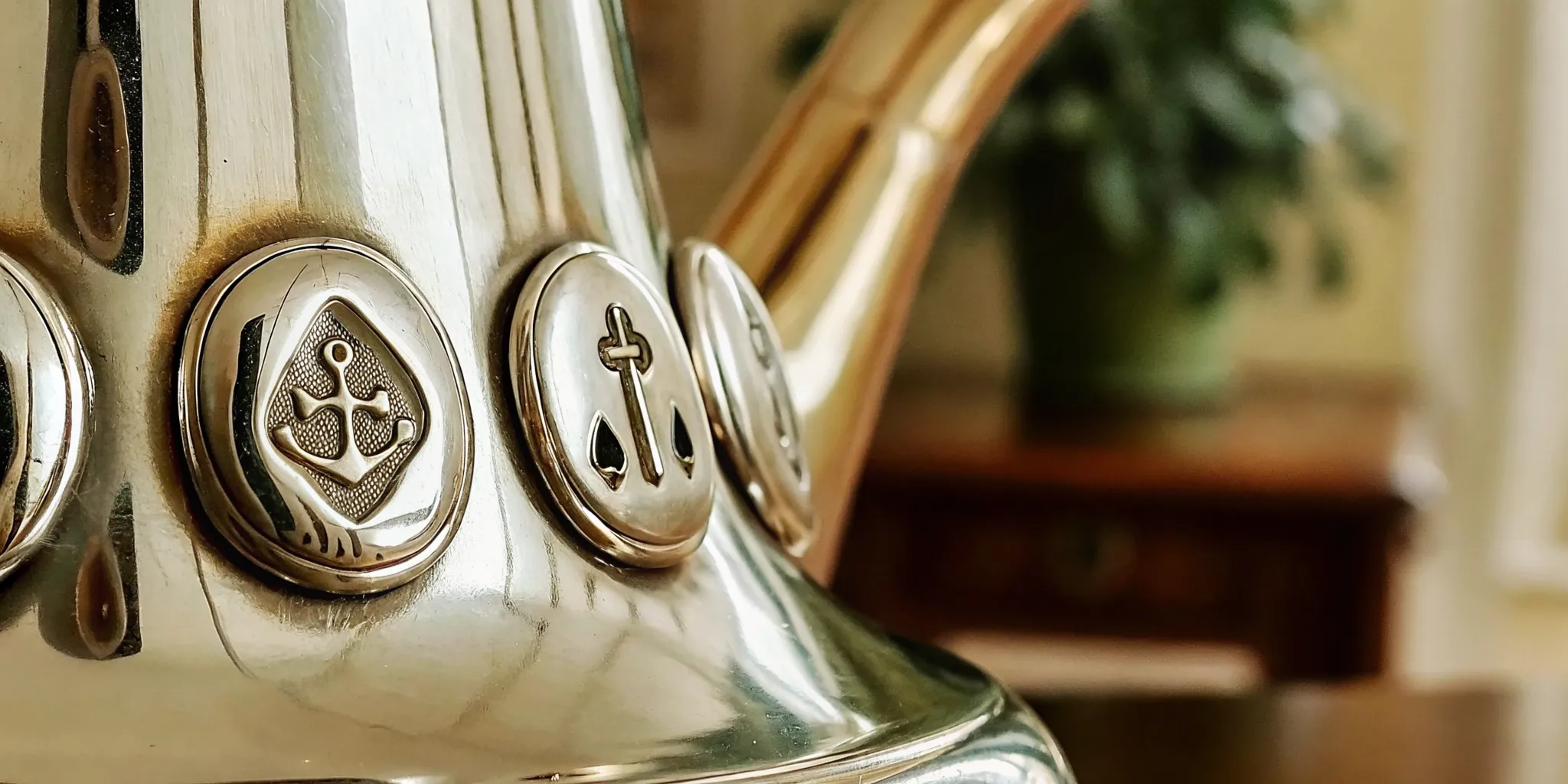 Close-up macro photograph of antique silver hallmarks showing a lion passant, anchor, date letter, and maker marks stamped on polished silver
