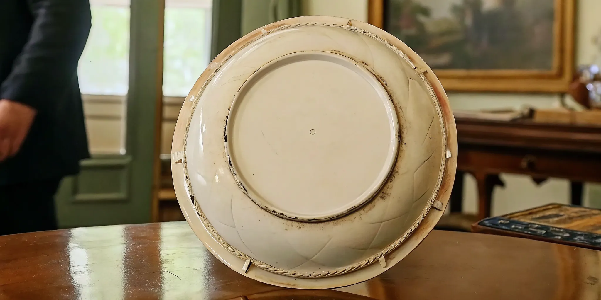 Collector examining factory marks on antique Limoges porcelain
