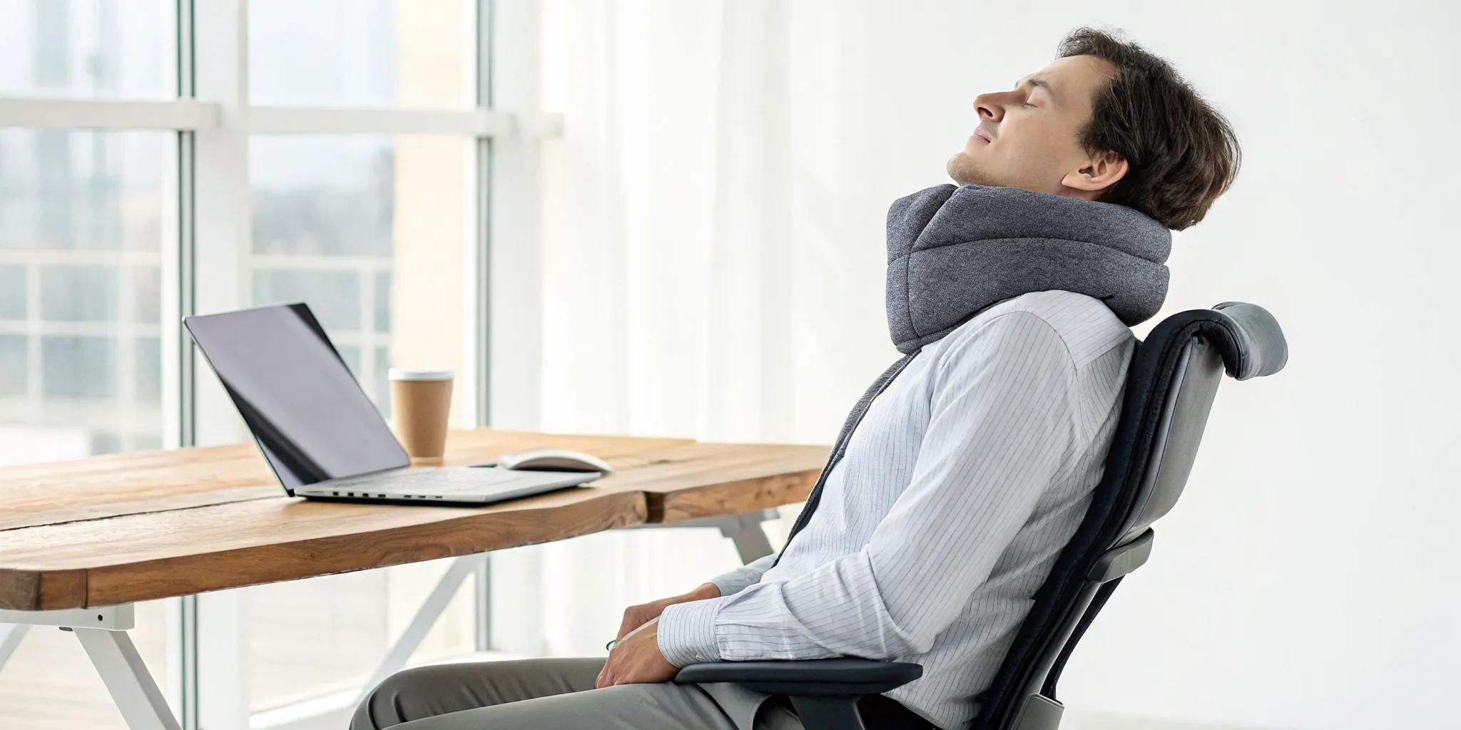 Man in an office chair relieving tension headaches from neck pain with a neck pillow.