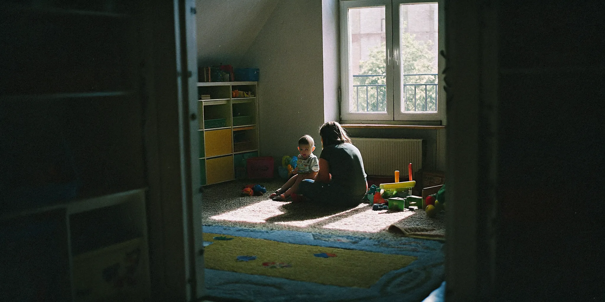 Child playing with building blocks while a parent reads nearby, illustrating a calm focused environment for neurodiverse children